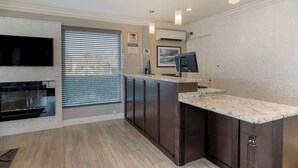 A modern kitchen with dark cabinets, a marble countertop, and a built-in oven. - Best Western Orange Plaza (Orange)