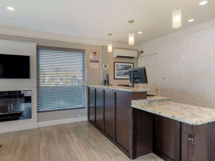 A modern kitchen with dark cabinets, a marble countertop, and a built-in oven.