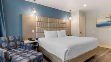 Una habitación de hotel moderna con una cama grande, una mesita de noche, una silla y un cuadro en la pared.