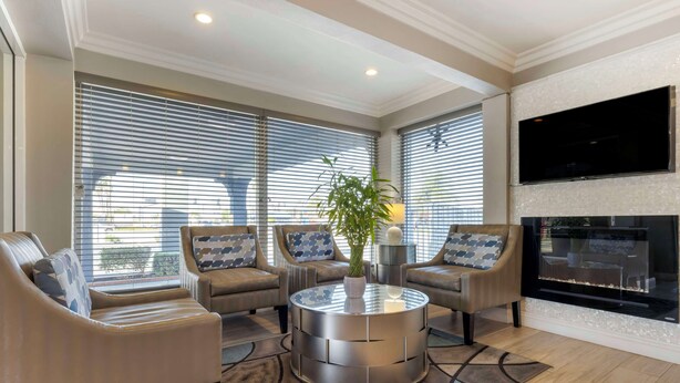 A modern living room with a round coffee table, two sofas, a TV, and a fireplace. - Best Western Orange Plaza (Orange)