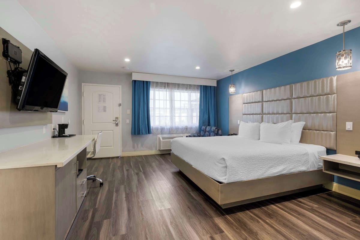 Une chambre d’hôtel moderne dotée d’un grand lit, d’un bureau, d’une télévision à écran plat et d’une fenêtre avec des rideaux.