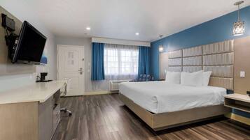 Una habitación de hotel moderna con una cama grande, un escritorio, un televisor de pantalla plana y una ventana con cortinas.