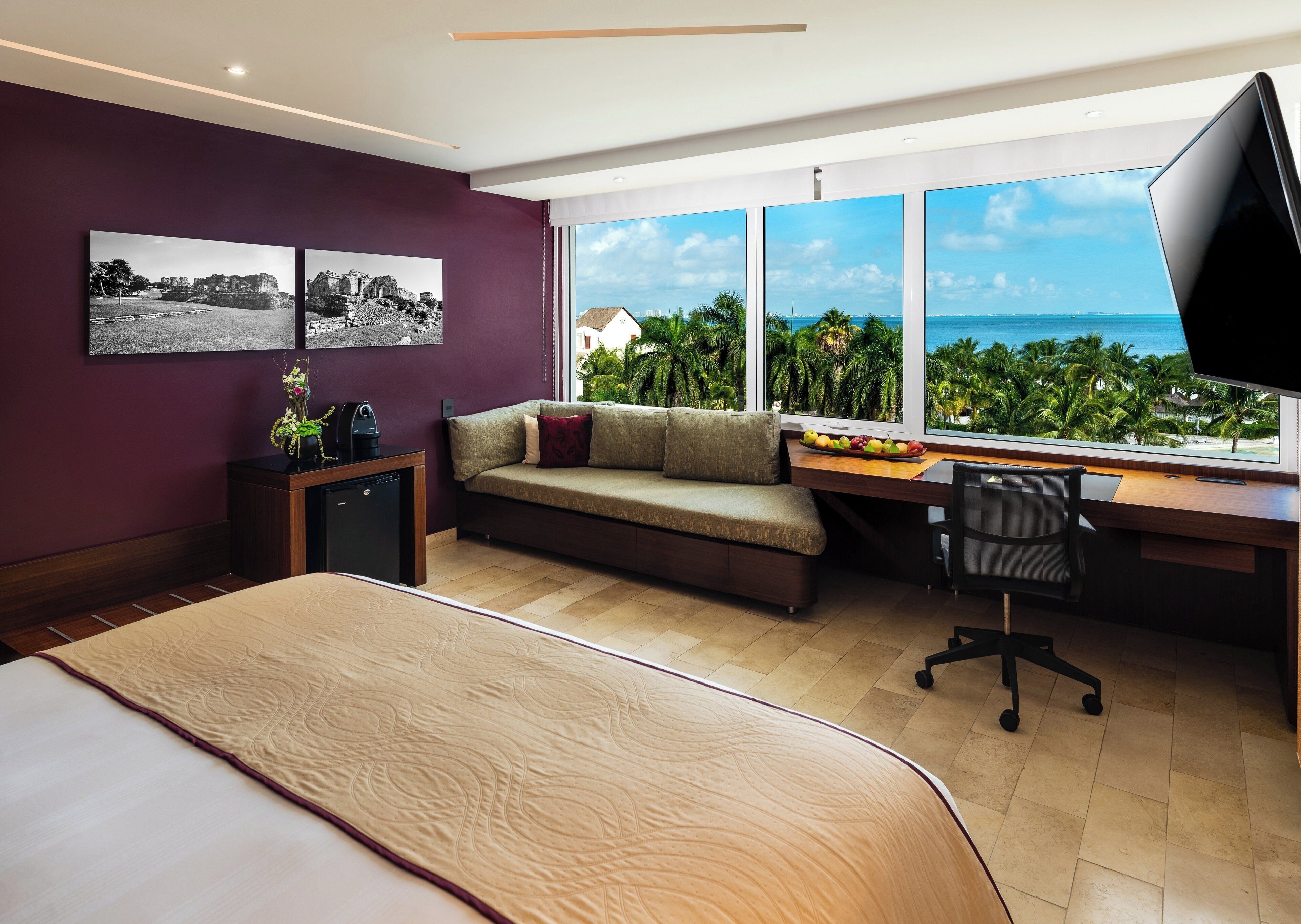 Een moderne hotelkamer met een groot bed, een sofa, een bureau met een computer en uitzicht op de oceaan.