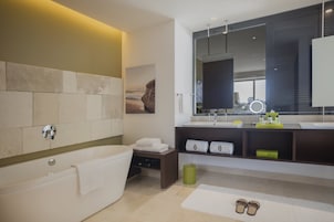Un bagno moderno con una vasca, uno specchio grande e un mobile lavabo con lavandino e spazio per asciugamani.