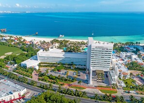 A hotel with a large building, a parking lot, and a beach in the background. - InterContinental Presidente Cancun Resort by IHG (Cancun)