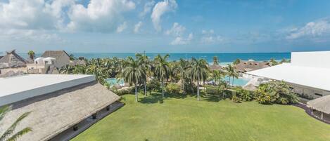 Un resort con piscina, palmeras y vista al océano.