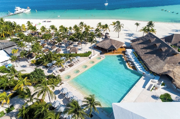 An aerial view of a resort with a large pool, beach, and thatched-roof structures. - InterContinental Presidente Cancun Resort by IHG (Cancun)