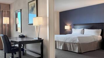 A hotel room with a bed, desk, chair, and two bedside lamps.