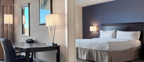 A hotel room with a bed, desk, chair, and two bedside lamps.