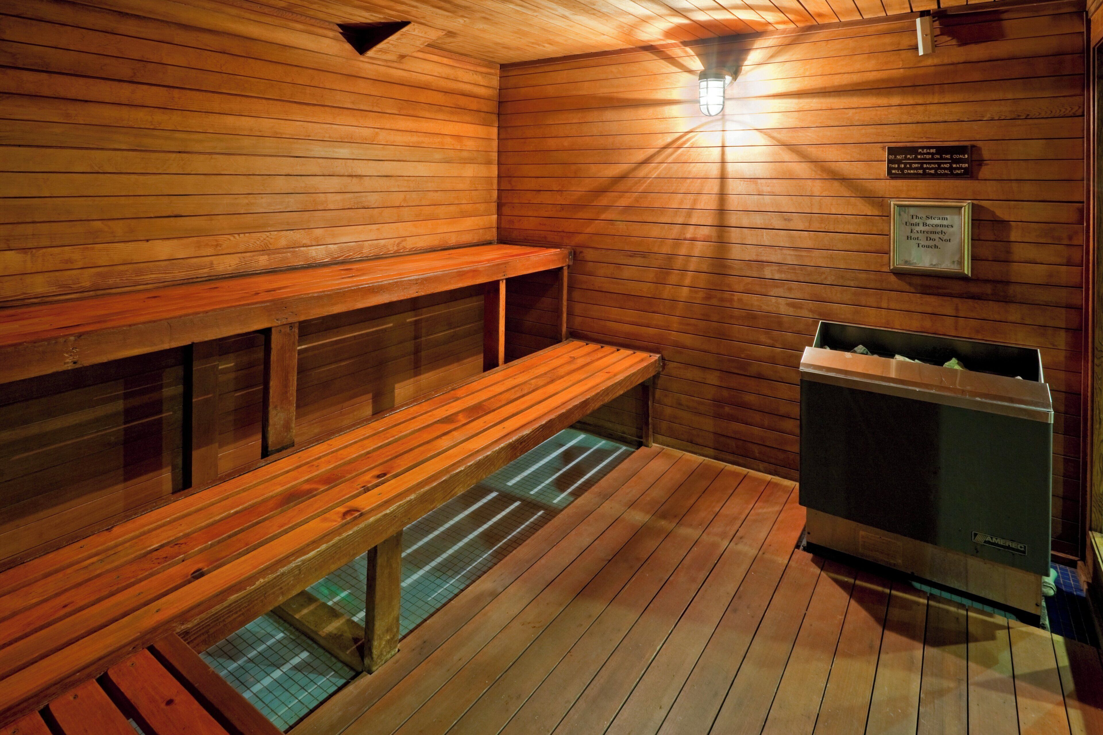 A sauna room with wooden benches and a steam unit.
