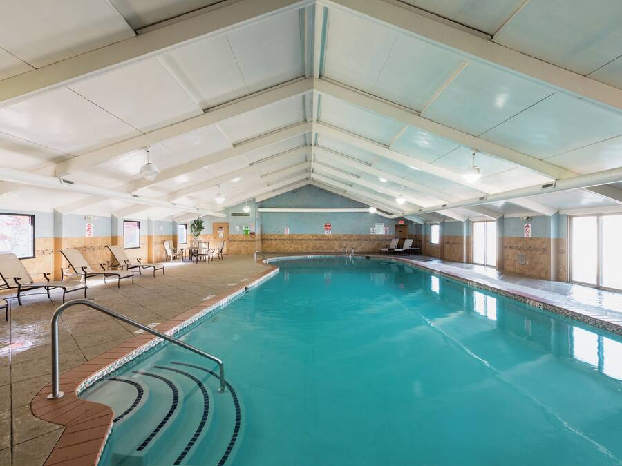 An indoor swimming pool with clear water, tiled walls, and a ceiling with visible ductwork.