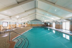 An indoor swimming pool with clear water, tiled walls, and a ceiling with visible ductwork.