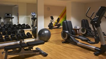 A gym with exercise equipment, a mirror, and a clock on the wall.