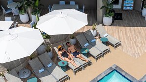 Un espace aménagé au bord de la piscine, avec des chaises longues, des parasols et une piscine.