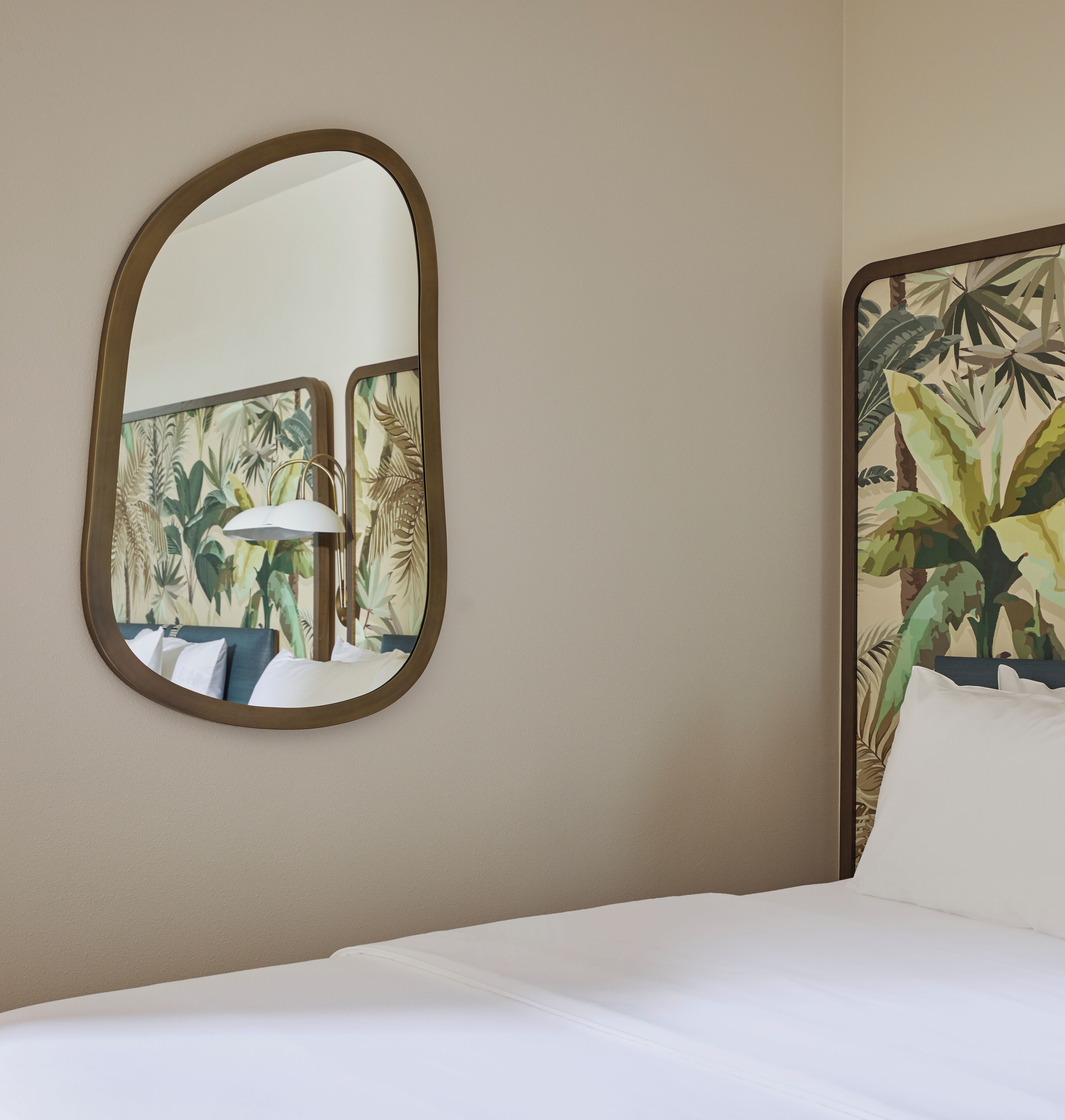 Una camera da letto con un letto, uno specchio a parete e una testiera a tema tropicale.