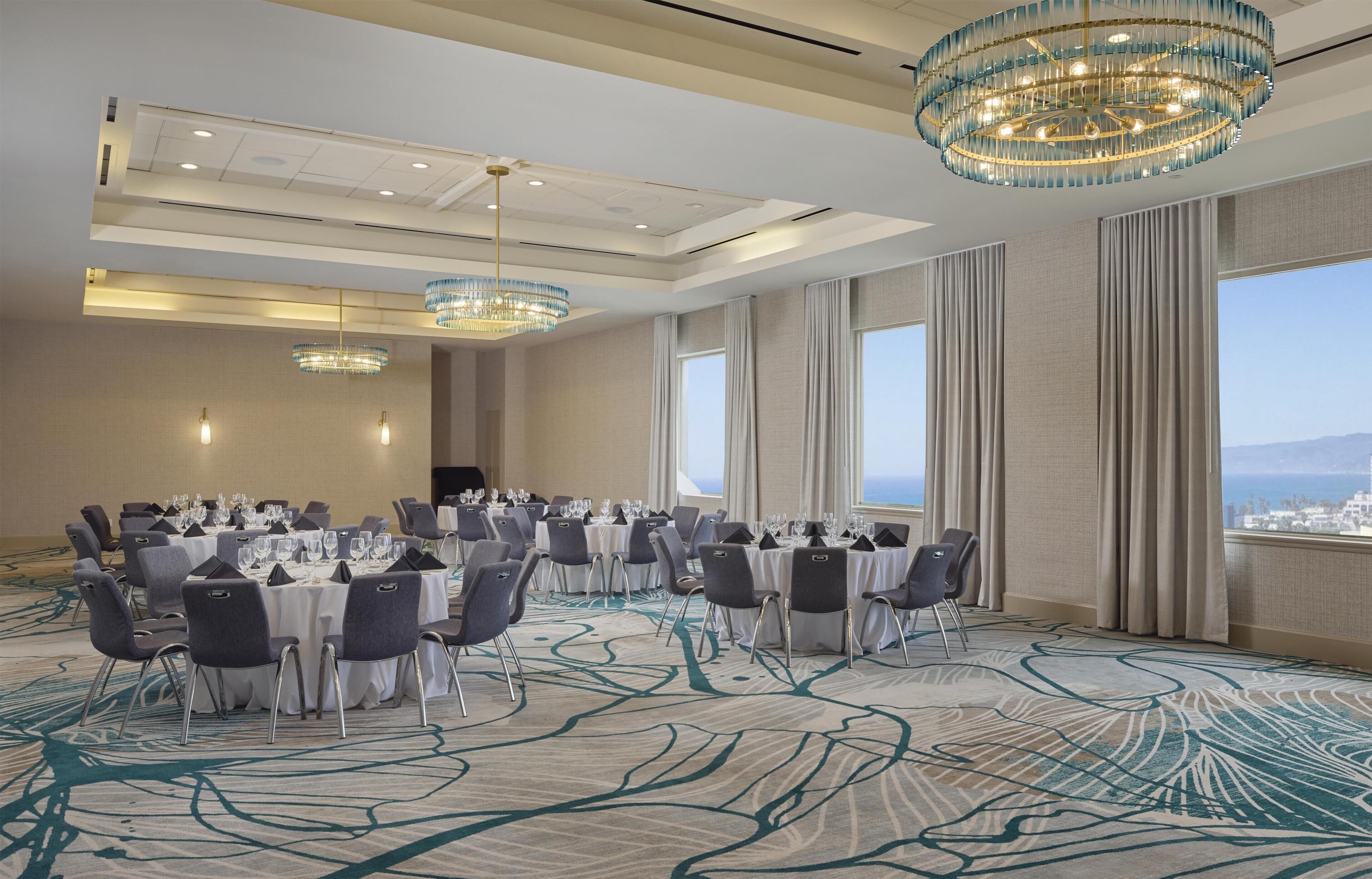 A conference room with round tables, chairs, and chandeliers.
