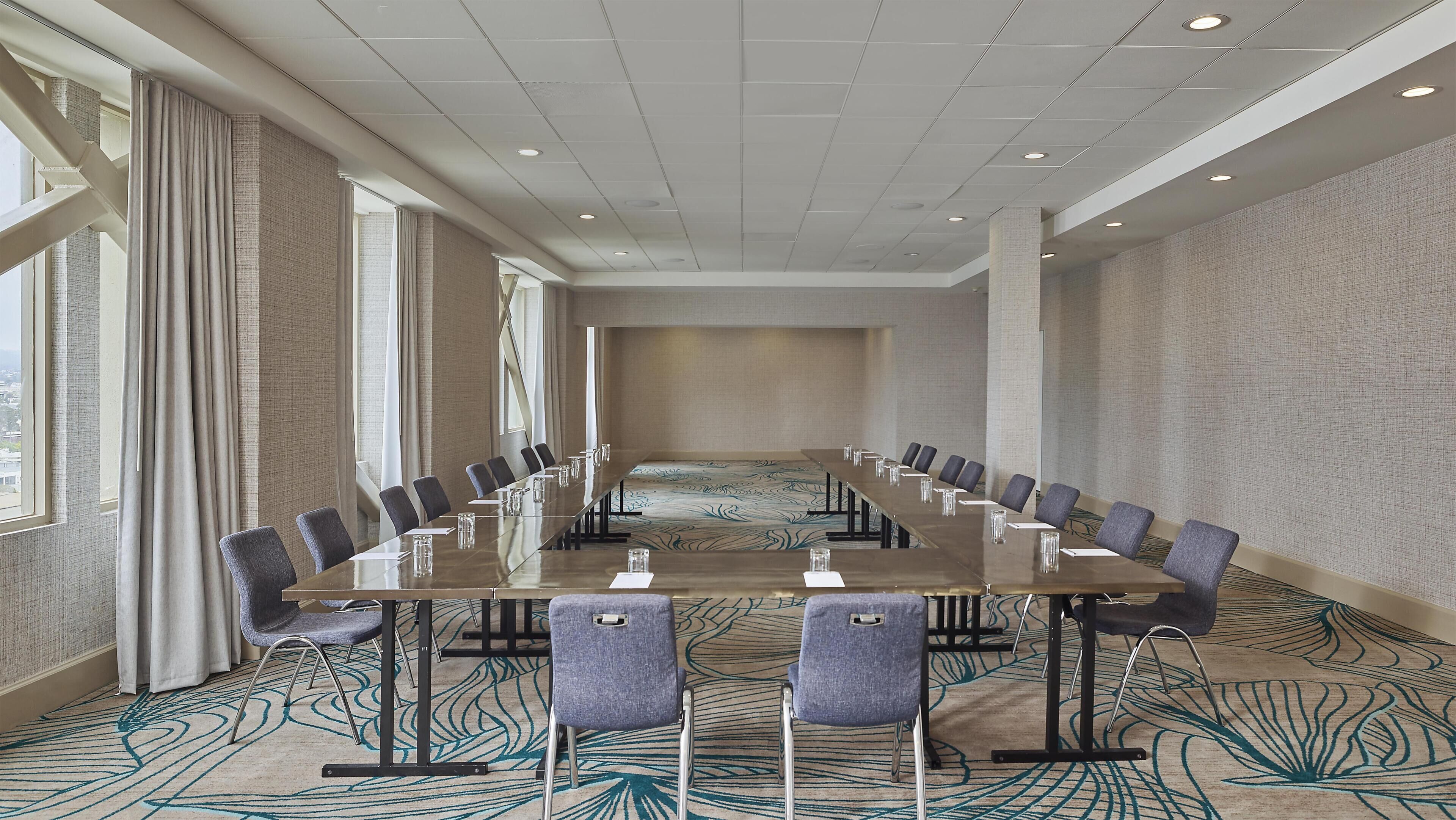 A conference room with a long table, chairs, and a patterned carpet.