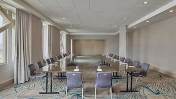 A conference room with a long table, chairs, and a patterned carpet.