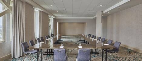 A conference room with a long table, chairs, and a patterned carpet.