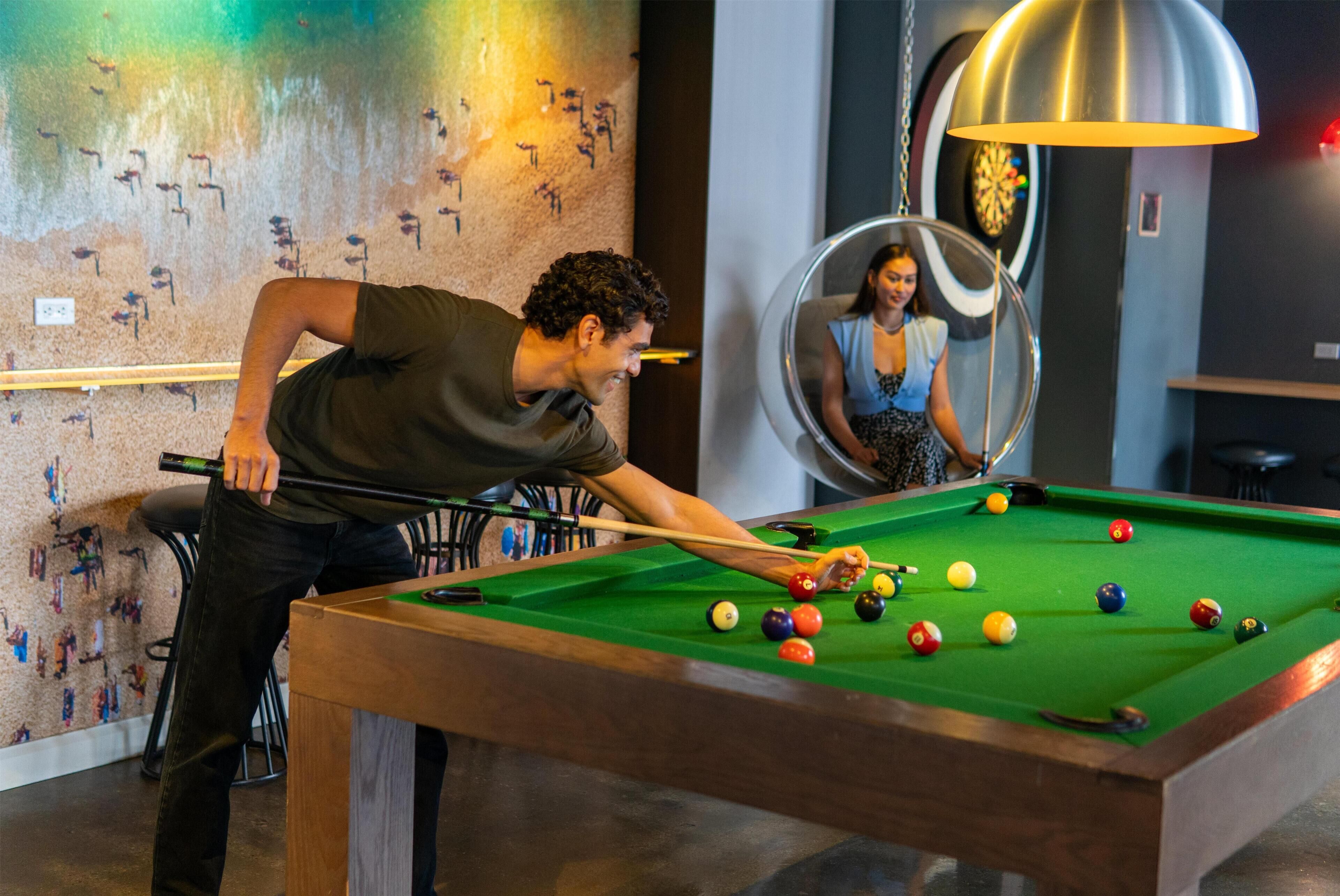 Une table de billard avec des billes, un jeu de fléchettes et un grand miroir.
