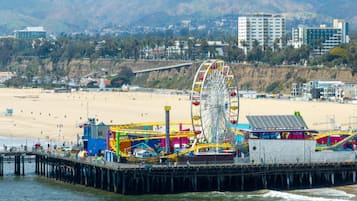 A pier with a Ferris wheel, beach, and buildings in the background.