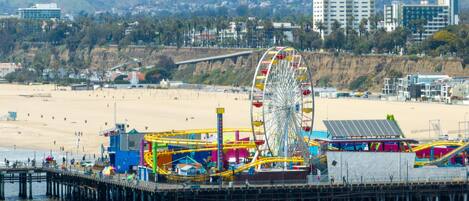 A pier with a Ferris wheel, beach, and buildings in the background.