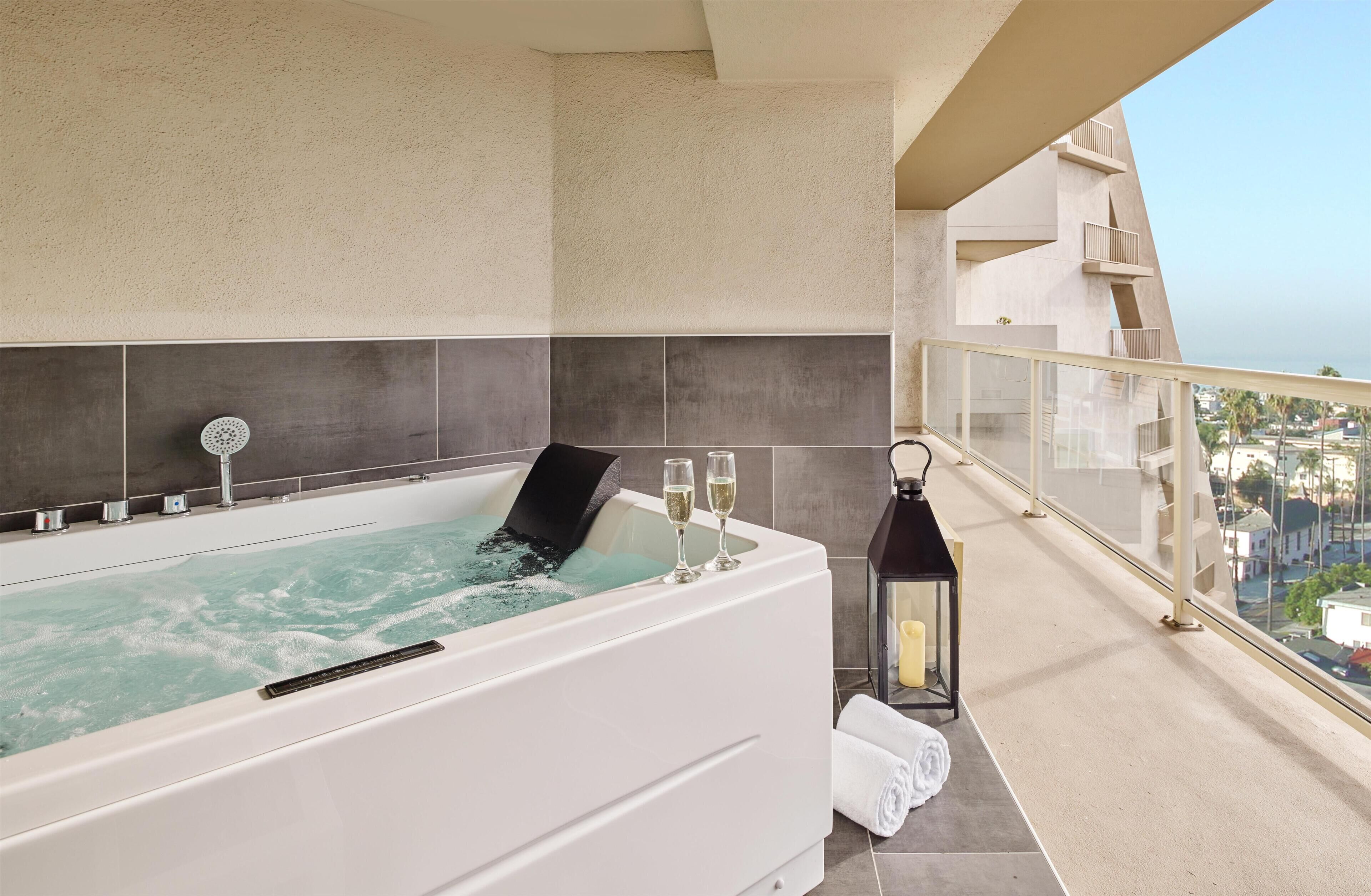 Une salle de bain moderne dotée d’un jacuzzi, d’un balcon vitré et offrant une vue sur la ville.