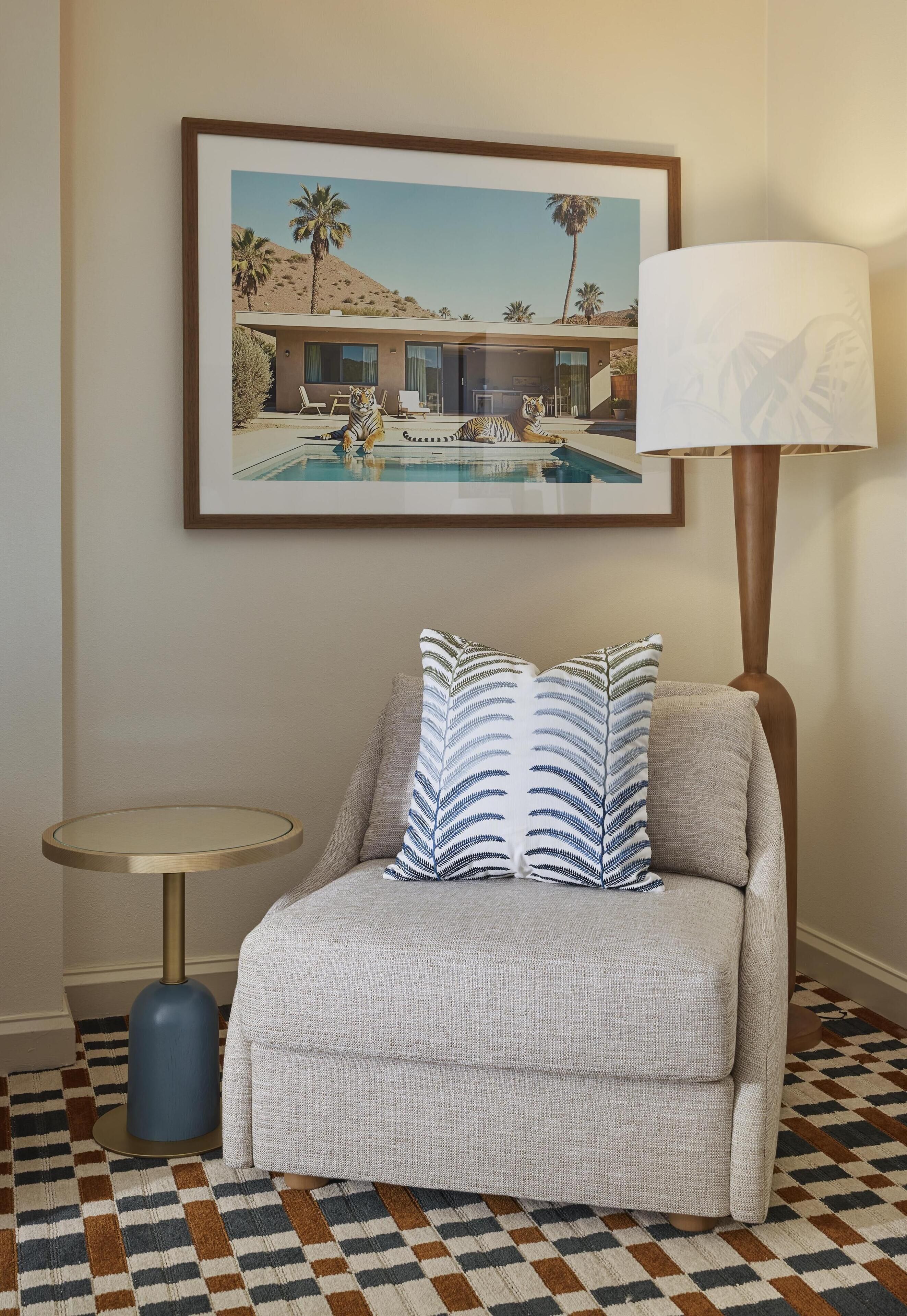 A room with a sofa, a small round table, a lamp, and a framed picture on the wall.