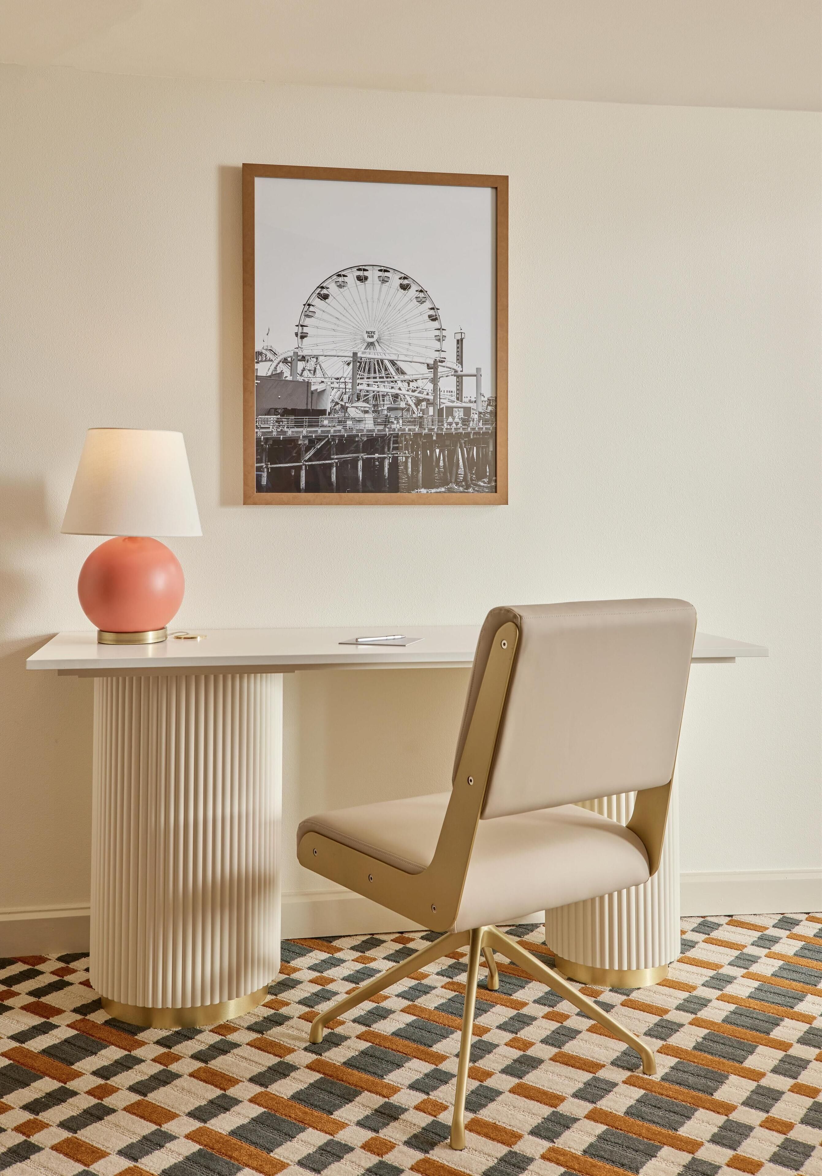 Une pièce avec une table blanche, une chaise, une lampe et un tableau représentant une grande roue.