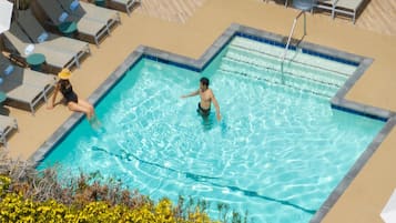 A rooftop pool with a clear view of the sky, surrounded by lounge chairs and umbrellas.