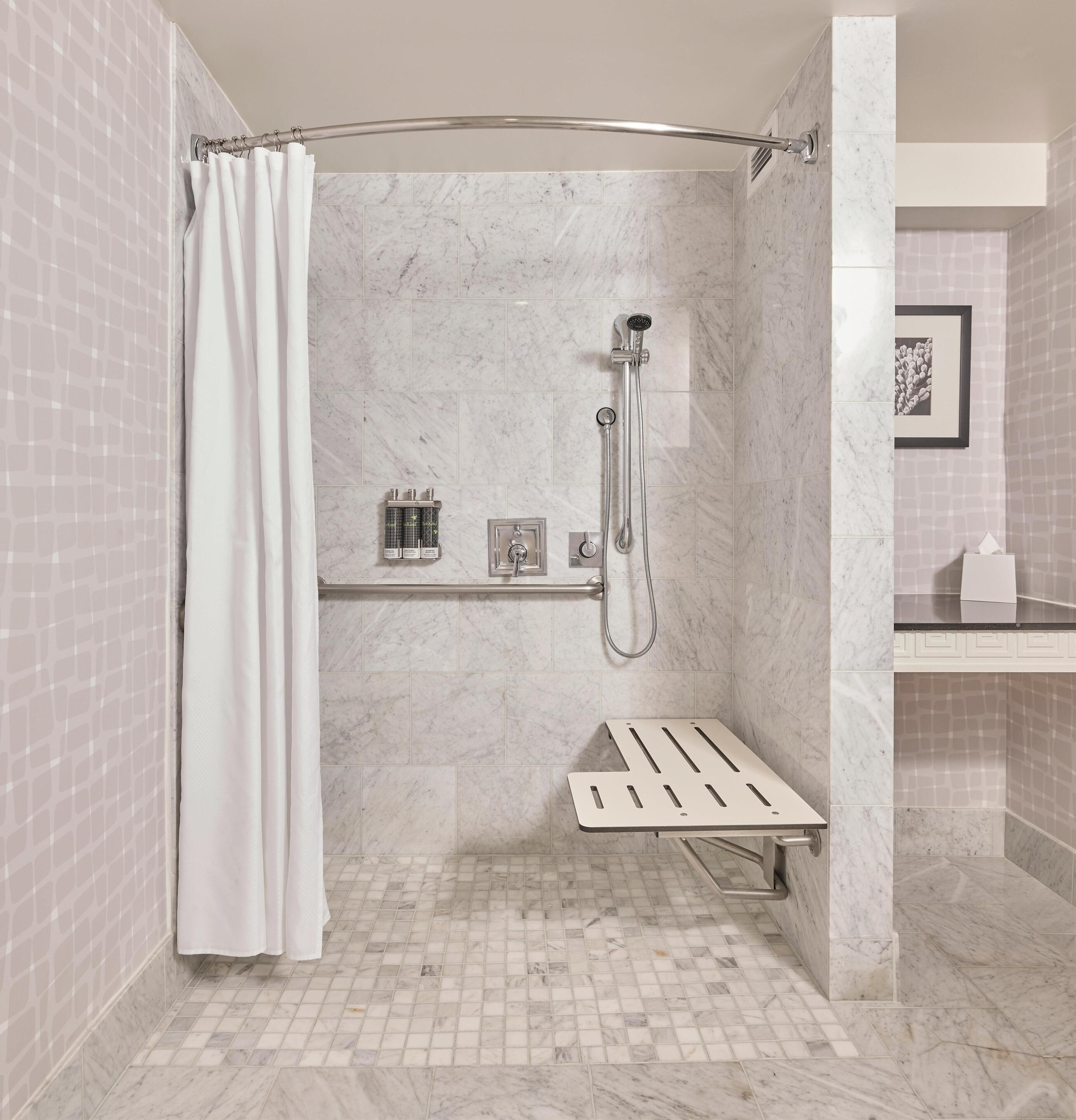 A modern bathroom with a shower, a towel rack, and a small shelf.
