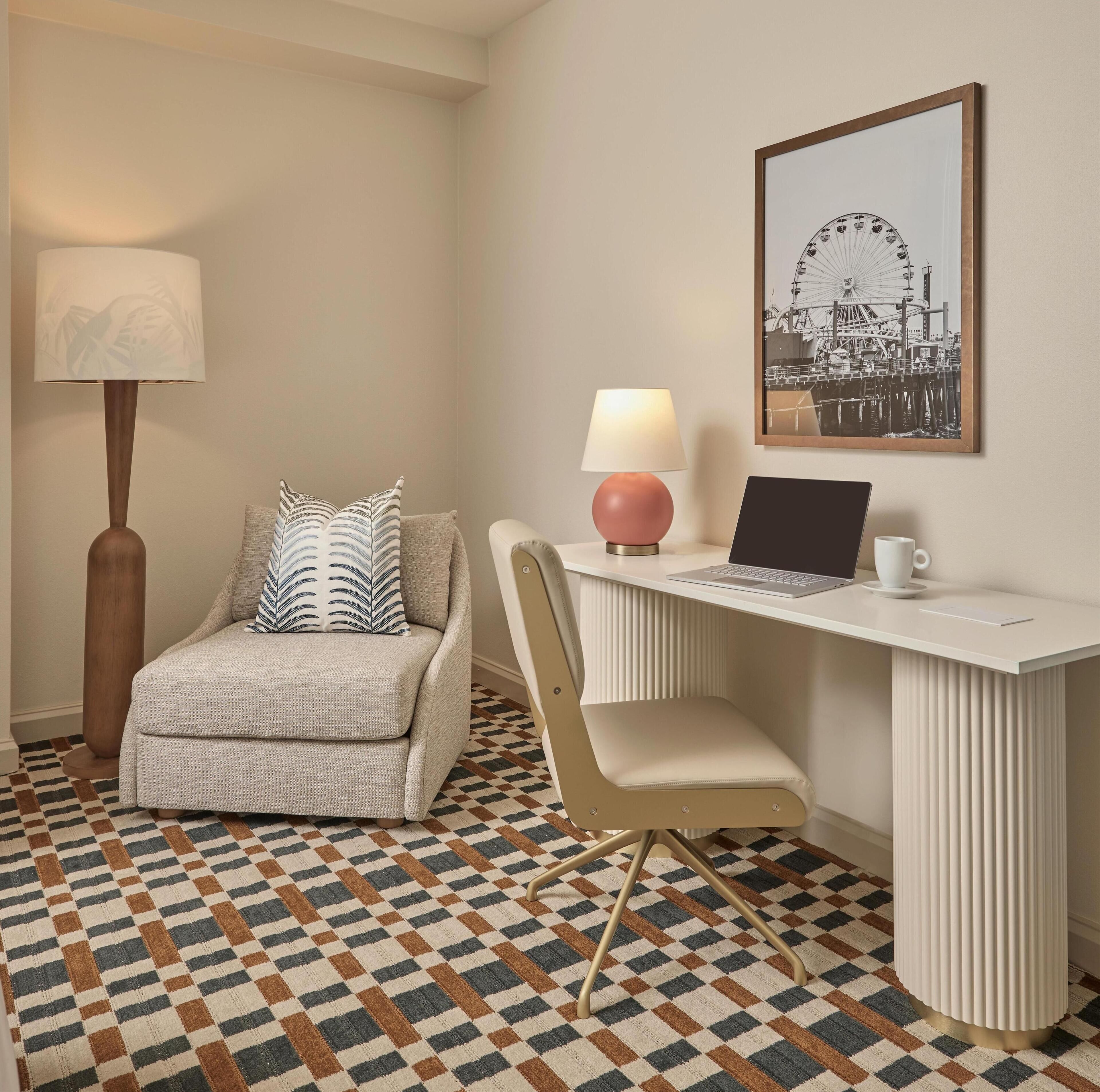 Habitación moderna con escritorio, silla, lámpara, ordenador portátil y un cuadro con una noria.