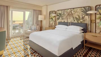 Habitación de hotel con una cama grande, un escritorio, una silla, una lámpara y vistas al exterior.