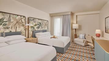 A hotel room with two beds, a desk, a chair, a patterned floor, and artwork on the walls.