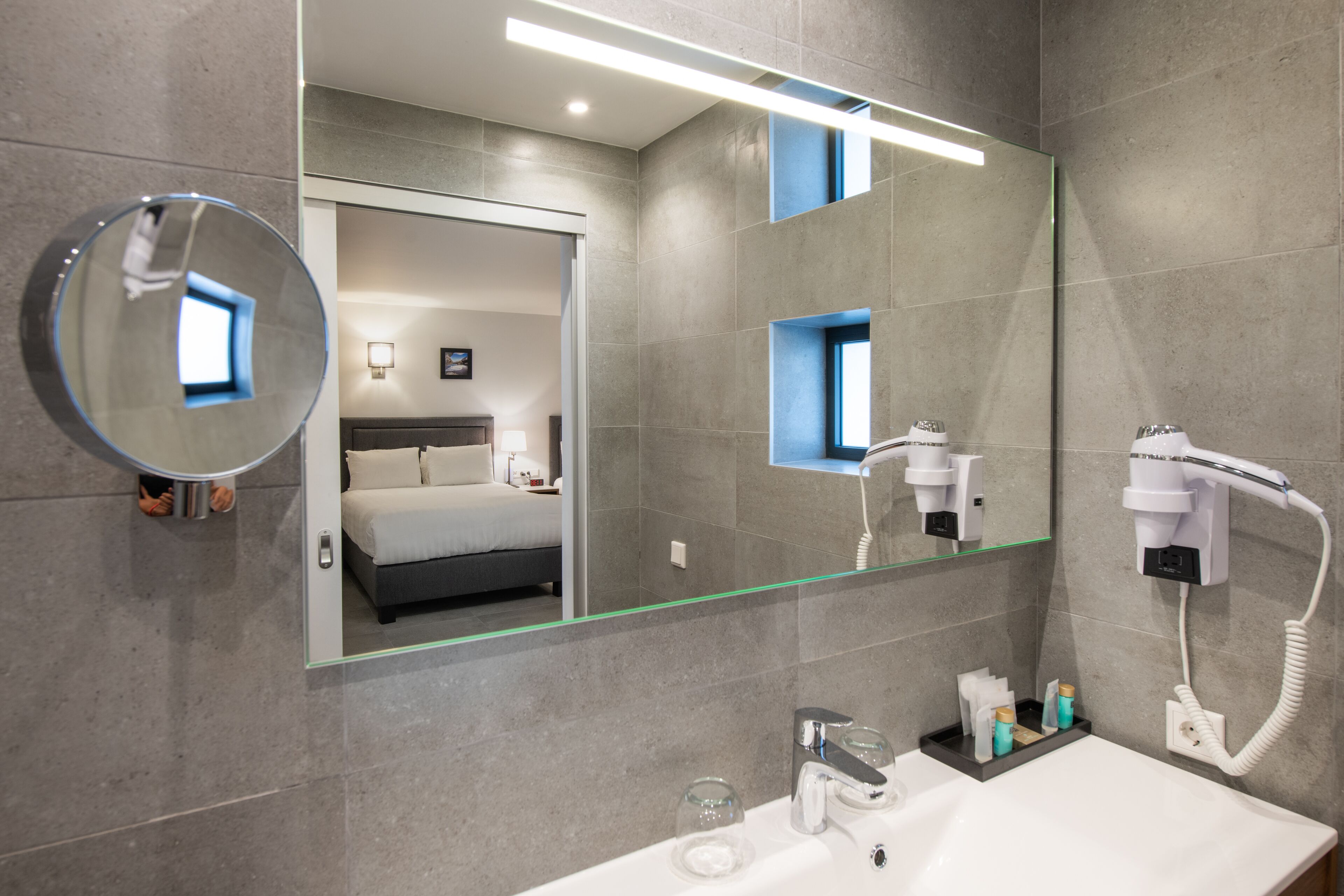 Un bany modern amb un mirall gran, un assecador i un lavabo.