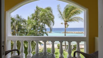 Een balkon met uitzicht op de oceaan en palmbomen.