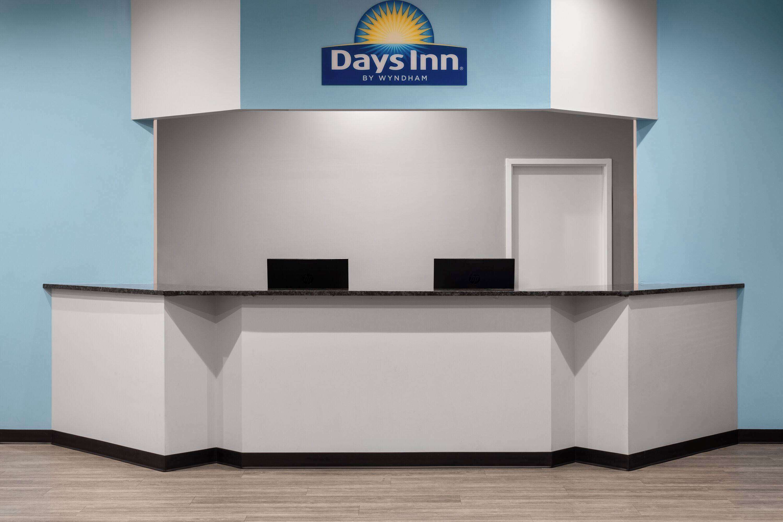 Ein Empfangsschalter mit Days Inn Logo, einem Flachbildfernseher und einer Tür.