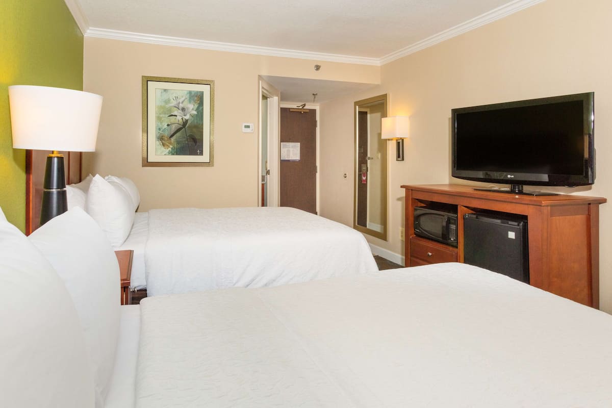 A hotel room with two beds, a television, a microwave, and a refrigerator.