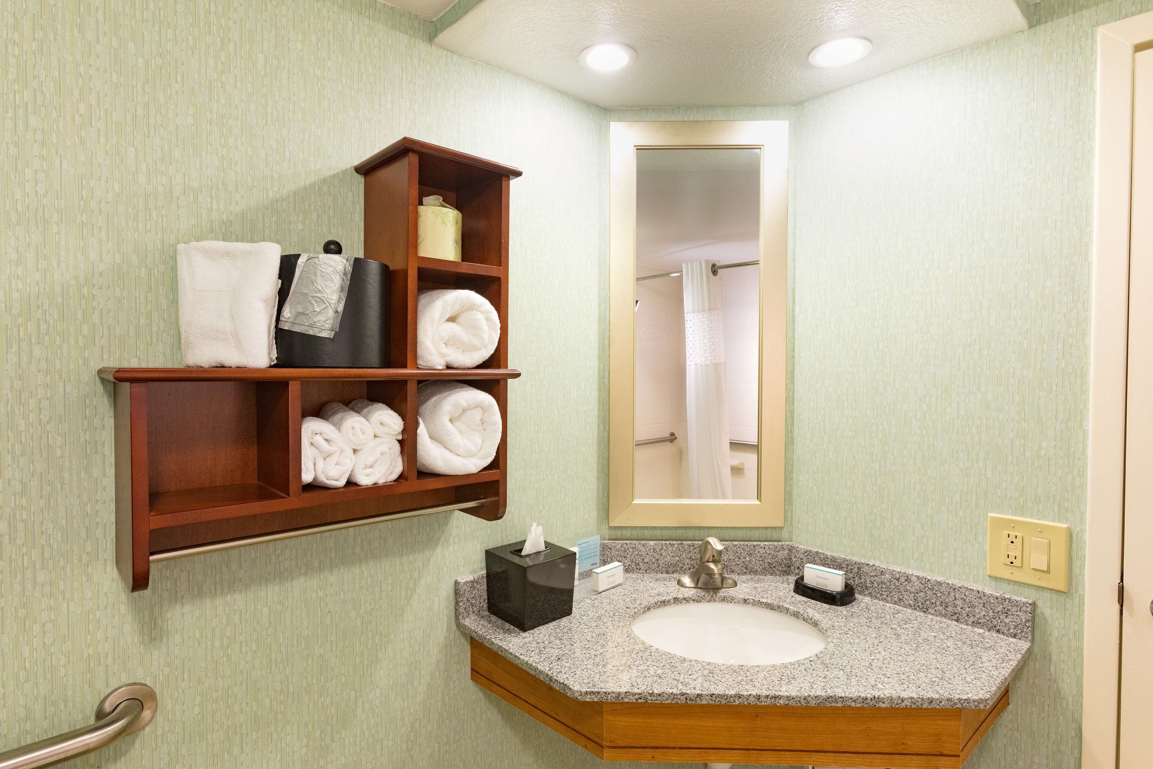 Une salle de bain avec un lavabo en granit, un miroir, un porte-serviettes avec des serviettes pliées et un boîte à mouchoirs.