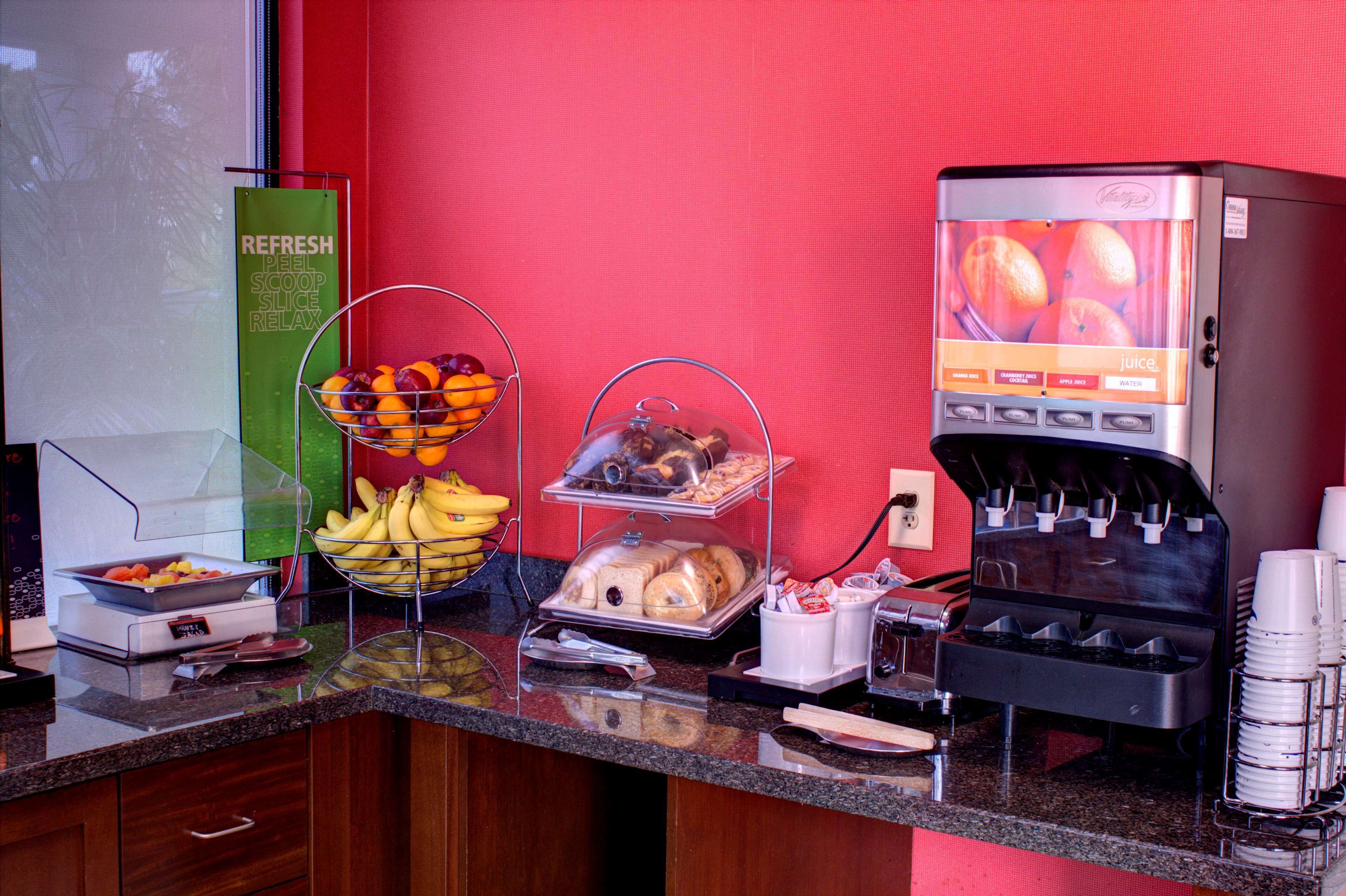A breakfast buffet with various food items and a juice dispenser.