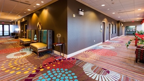 A hotel lobby with a patterned carpet, seating area with chairs, and a reception desk.