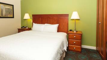 A neatly made bed with a wooden headboard, two bedside tables with lamps, and a green wall.