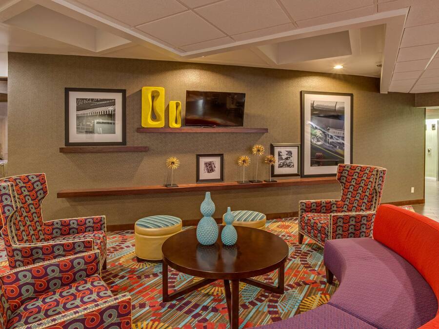 A hotel lobby with patterned armchairs, a round table, and wall-mounted artwork.