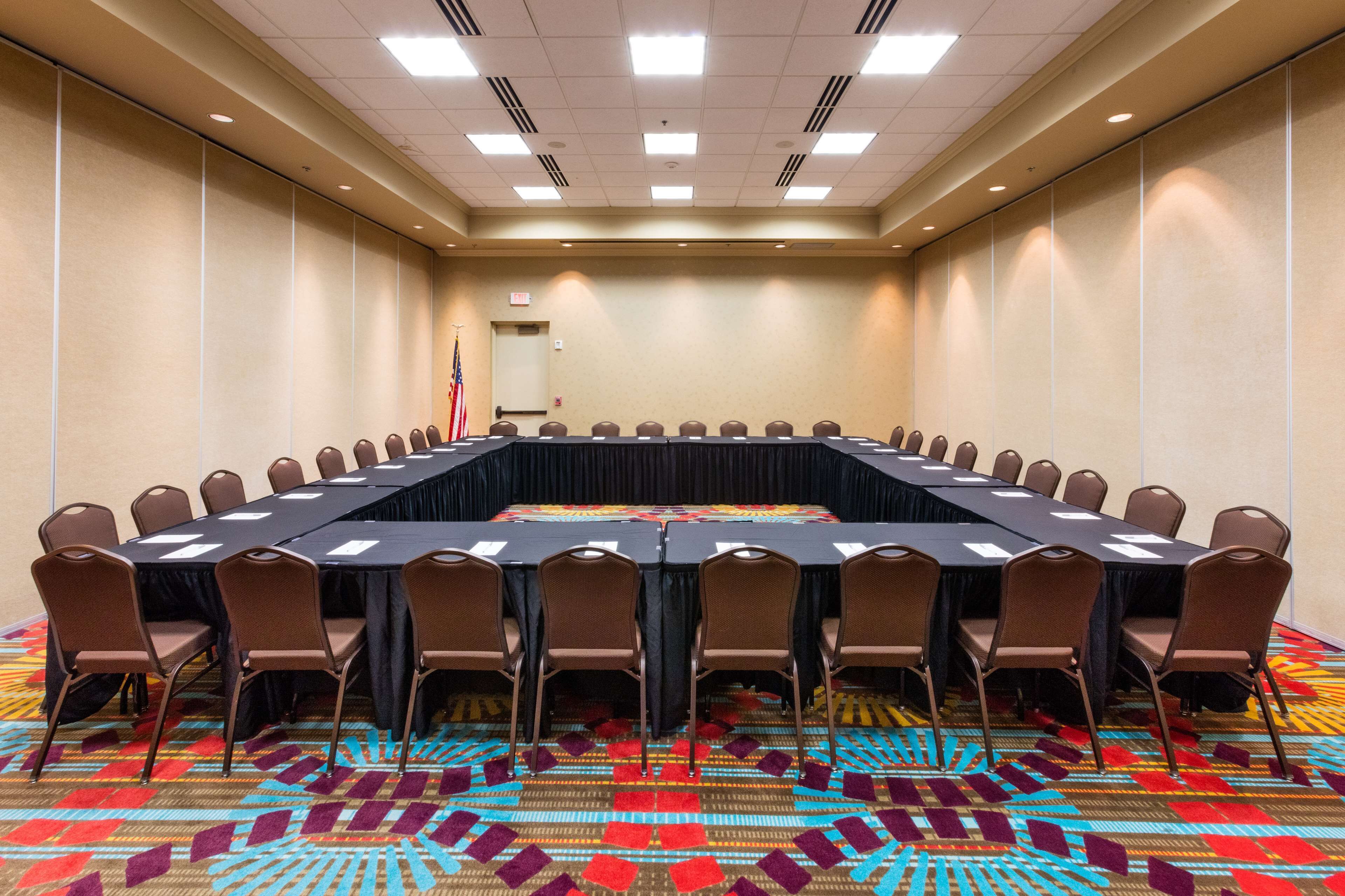 Une salle de conférence avec une longue table, des chaises et un tapis à motifs.
