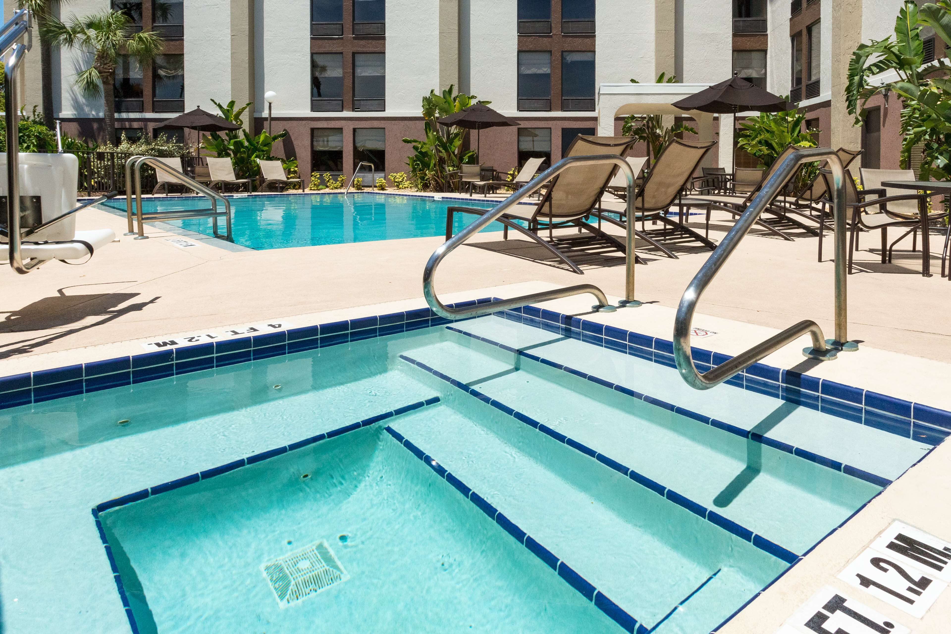 A pool area with clear blue water, lounge chairs, and umbrellas.