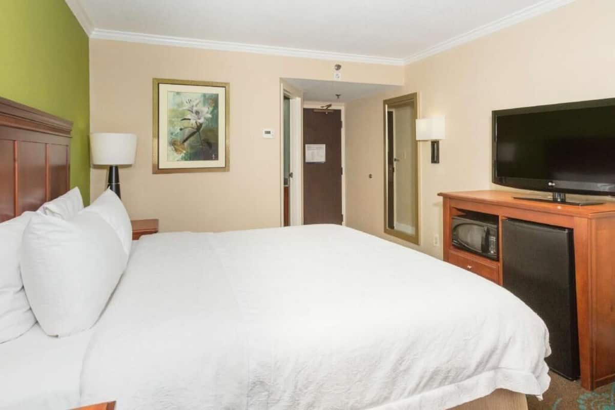 A hotel room with a bed, a television, a microwave, and a door leading to another room.