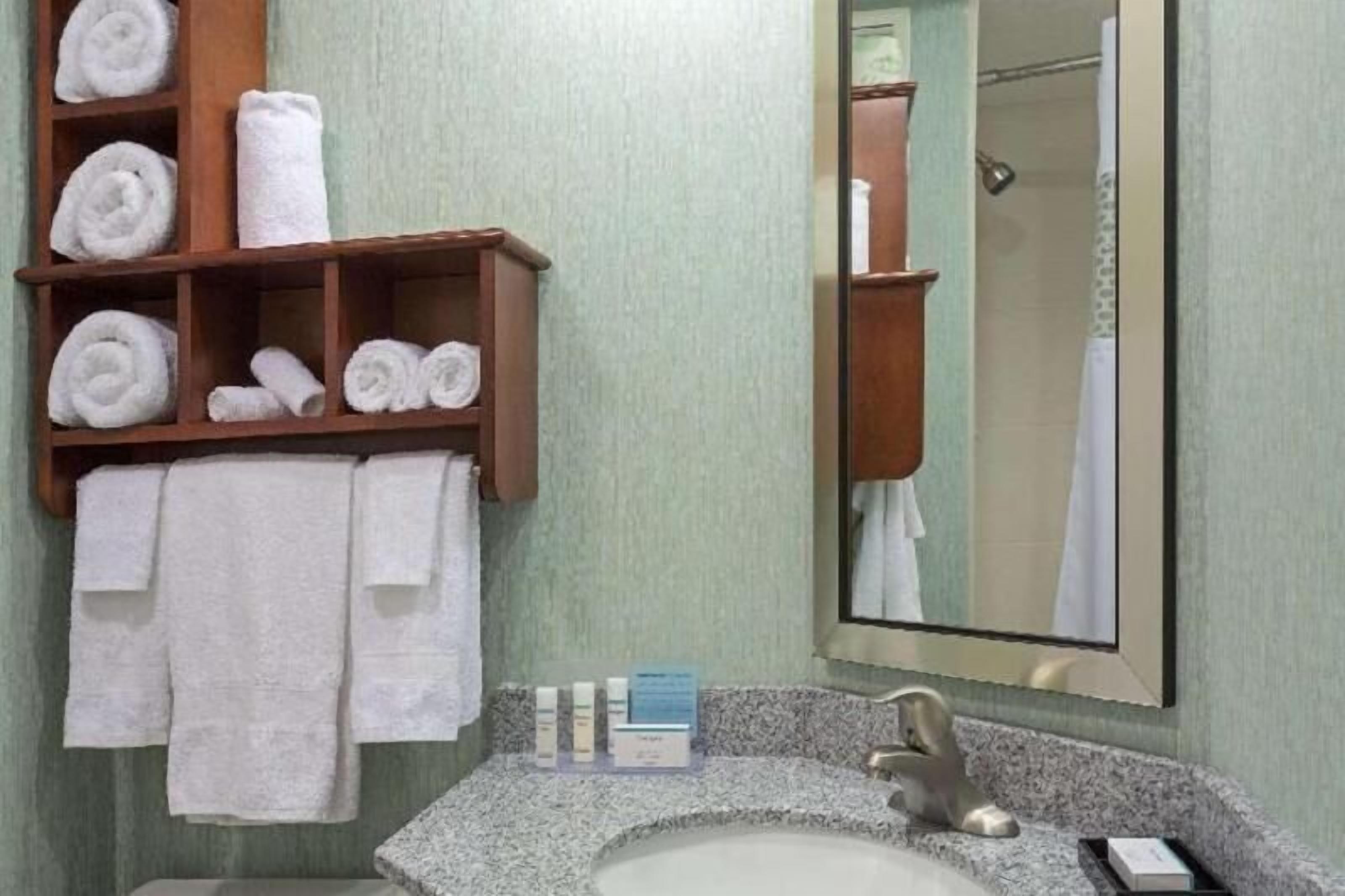 Casa de banho com lavatório, espelho, porta-toalhas e artigos de higiene.