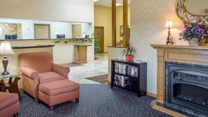A lobby with a reception desk, a fireplace, a sofa, a bookshelf, and a mirror.