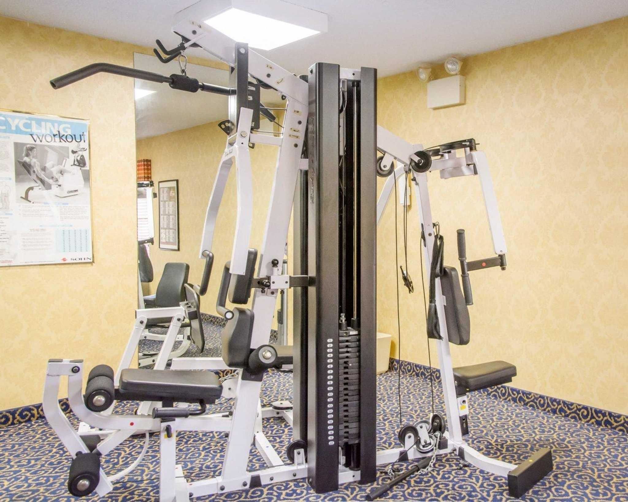 A gym with various exercise machines, a patterned carpet, and a poster on the wall.