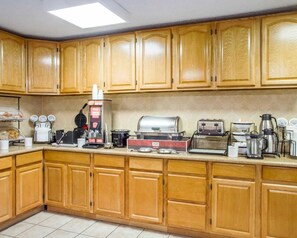 A kitchen with wooden cabinets, a coffee machine, a toaster, and a grill.